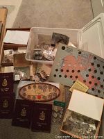 Overview of lot: plastic tub and boxes containing coins, coin booklets, stamps and banknotes on carpet