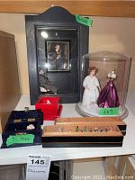 Full view of all diorama components: wood framed diorama, glass dome with figures, and three black boxes with miniatures