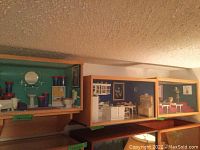 Three dioramas displayed on shelves: bathroom, kitchen, and doctor classroom