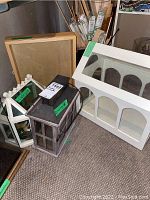 Photo showing several display boxes and a wood shadow box on the floor near art supplies and canvas stretchers.