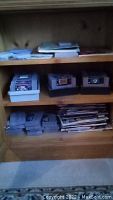 Wooden shelf with multiple SNES cartridges and stack of magazines on lower shelf