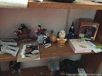 Shelf with various Harry Potter themed figurines including Harry flying on a broomstick, Hermione reading, Hedwig, and others, along with a cardboard picture frame and note pad.
