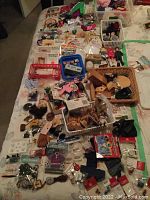 Overview of assorted miniature doll accessories including various small items laid out on a bed.