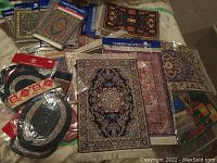 Photo showing multiple miniature Turkish woven carpets and rugs, many sealed in packaging, with diverse traditional patterns and colors.