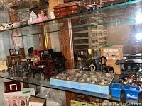 Shelf displaying a variety of miniature furniture, tea service items, and kitchenware including dining set, cabinets, and decorative miniatures.