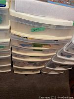 Photo of resin storage cabinet drawers labeled with contents like 'SAND'.