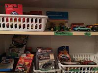 Shelf with assorted packaged toy cars from Matchbox, Modifiers, Corgi, Hot Wheels, and others, with white sorting trays (not included) and various small vehicles.