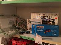 Photo of boxed Plasticville Classic Streetcars, CREATOLOGY train gondola kit, plastic farm miniatures and other train model kits on shelf with HO scale Plasticville label.