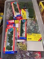 Storage bin with unopened Noch branded miniatures model trees in original packaging and sealed plastic bags.