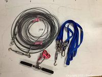 Full view of zip line cable coiled with stainless hardware, blue straps and handlebar