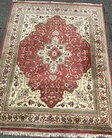 Full view of rectangular Persian rug showing central rose medallion and ornate patterned border in beige and rose colors