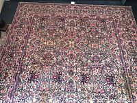 Full view of the rectangular wool area rug showing overall floral and vine pattern in red, beige, and blue.
