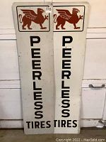 Pair of two vertical Peerless Tires signs side by side, showing full front view and condition.
