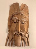 Frontal view of the carved wood mask showing facial features and headdress details