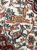 Close-up of animal motifs including a spotted animal and another four-legged creature in the rug's design.