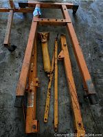 Disassembled parts including steel frame, cylinder, boom and extensions on concrete floor