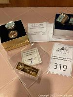 Photo showing all coins and commemorative pieces including 2016 Presidential Dollar coin package and Greatest U.S. President ingot, along with auction invoice and lot number card.
