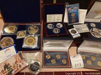 Overview of wooden cases, coin booklets, loose coins and medallions on tabletop