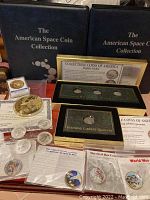 Two blue binders with the title 'The American Space Coin Collection', wooden coin storage box containing coins, Buffalo Nickel box set, and Standing Liberty Quarter box with accompanying informational cards.