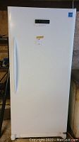 Front view of white upright freezer showing door, handle, digital control panel and MaxSold tag.