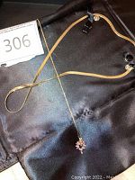 Overview of both chains on black fabric showing flat serpentine chain and cable chain with pendant