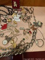 Assorted jewelry spread including 14K gold ring with blue stones, assorted necklaces, brooches, pins, chain link necklace