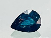 Pear cut deep blue sapphire on white surface