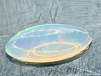 Close up of marquise cut translucent Ethiopian opal showing rich play-of-color and polished surface.