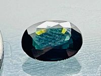Top view of oval cut deep green sapphire showing facets and color