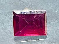 Close-up photo of a rectangular baguette cut Rhodolite Garnet gemstone showing color and clarity.