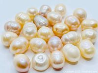 Close-up view of 35 natural freshwater pearls in cream and pink gold tones, mixed shapes and sizes.