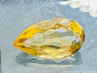 Close-up of the pear cut golden citrine gemstone highlighting its facet pattern and color.