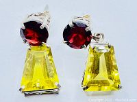 Close-up of front-facing earrings showing deep red round garnet stones and large yellow trapezoidal lemon quartz stones in sterling silver settings.