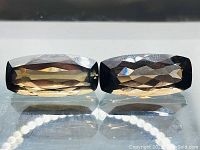 Two large rectangular faceted smokey quartz stones shown side by side, highlighting size, shape, and clarity.