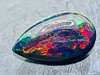 Top-side view of pear cabochon black opal showing multicolor flash