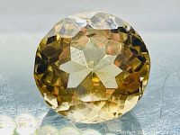 Close-up photo of the round, faceted golden citrine gemstone showing diamond cut facets and color.