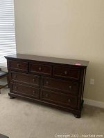 Seven-drawer dresser in dark brown finish against wall