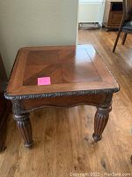 Side view of the wooden side table showing carved leg detail and square top