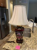 Full view of the table lamp with white fabric lampshade on granite counter near kitchen sink