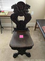 Front view of entire chair showing carved backrest, seat, and legs