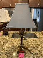Front view of vintage lamp on kitchen counter showing brass and wood base with pineapple detail and white tapered shade