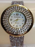 Front view of Dunking quartz gold plated watch with clear gemstone accents around bezel and on band, showing white dial with gold numerals and hands.
