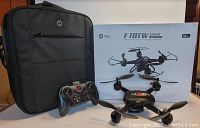 Photo showing Holy Stone F181W drone, remote controller, carrying bag, and product box on a table.