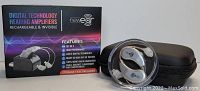 Photo of Newear boxed set showing digital hearing amplifiers, charging dock, and storage case.