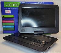 Black UEME branded 10.1 inch portable digital multimedia video player placed next to its product box which highlights key features such as USB port, SD card reader, DVD/CD playback, built-in rechargeable battery, and stereo speakers.