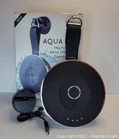 Photo of Wasserstein Aqua Dew Alexa Shower Speaker with its box, suction cup attachment, wrap-around strap, and USB charging cable.