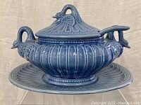 Blue ceramic swan-shaped tureen with lid, ladle, and round platter shown from multiple angles