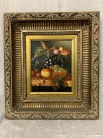 Full view of the framed oil painting showing a still life of fruit, including grapes, peaches, raspberries, and nuts.
