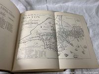 Open book showing a fold-out map titled 'The Town of Boston in New England' from 1722 with detailed drawings of Boston and surrounding areas including ship illustrations.