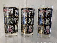Set of 3 glasses showing the Captain's Window motif with gold, black, blue, and pink paint on clear glass.